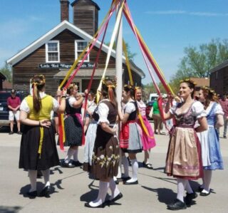 Ladies in period costume around maypole at Maifest