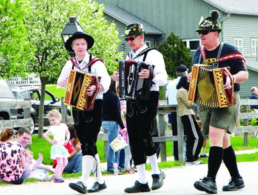 3 men walking and playing accordians at Maifest
